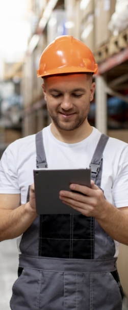 Smiley man hold a tablet in warehouse